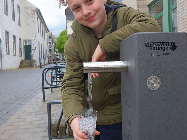 Ein Junge füllt sich Wasser in ein Glas
