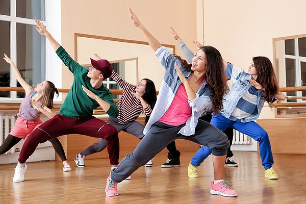 Gruppe von Jugendlichen tanzt mit Choreographie in einem Raum