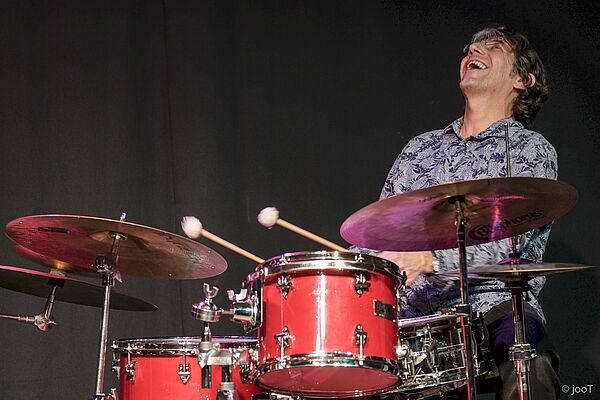 Peter Baumgärtner sitzt am Schlagzeug und lacht